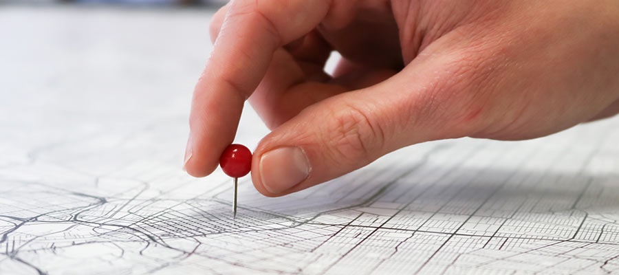 A person pushes a pin into a map.
